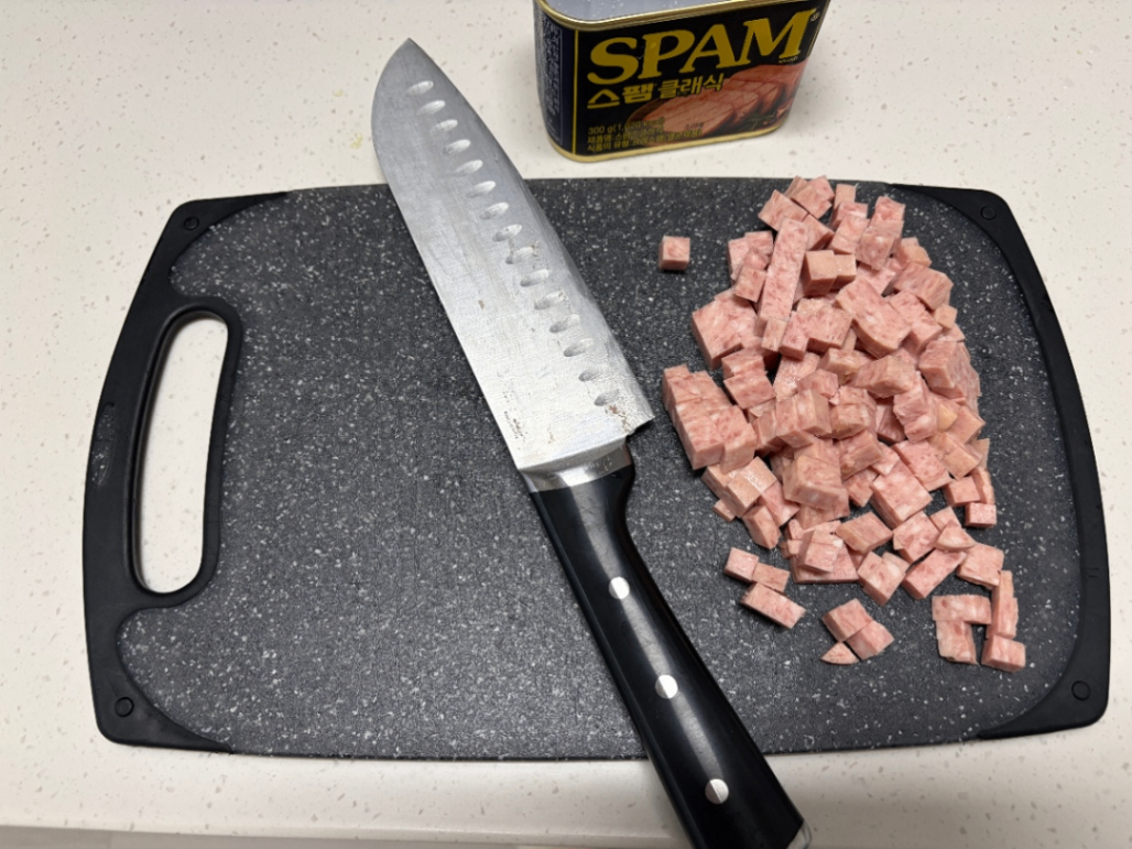 스팸을 도마 위에서 칼로 썰어준 사진